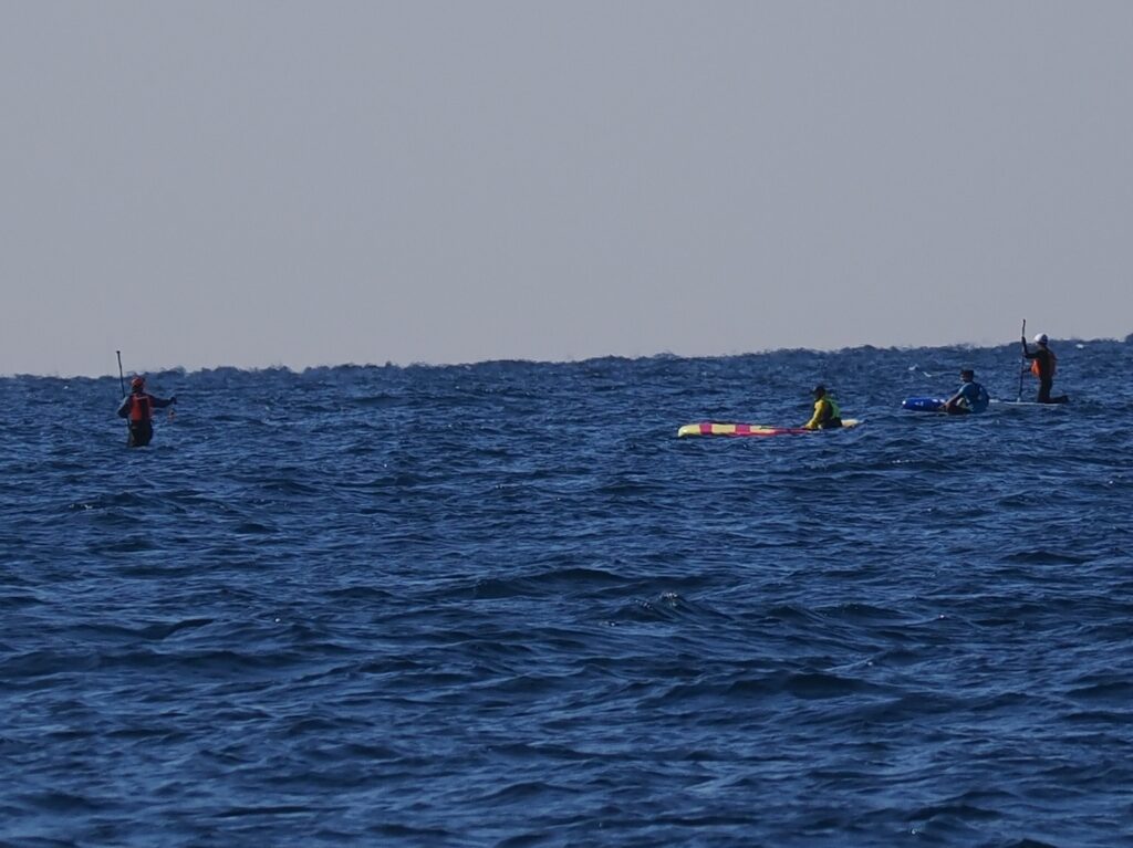東京湾の千葉沖をサップで移動する何人かの人たちが洋上で休んでいる。