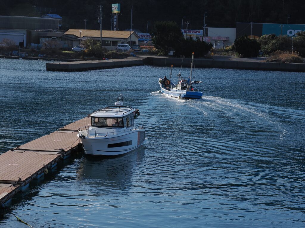 保田漁港の桟橋に係留する愛艇と、漁港から出ていこうとする漁船。