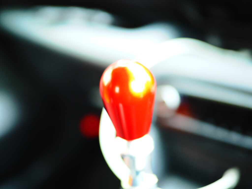 ZUIKO 25mm F1.2 絞り開放で撮影した紅いシフトノブの写真。