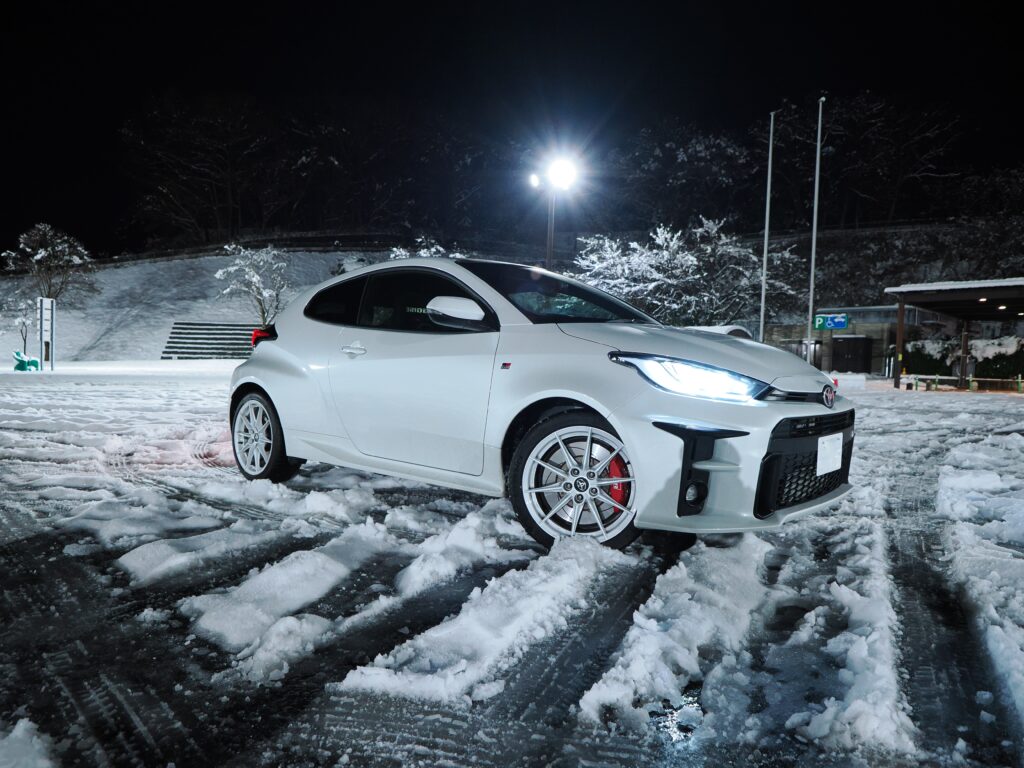 ワインディングに向かう高速道路のパーキングエリアで撮影したGRヤリス。路面に雪が残り、タイヤの跡が交錯している。